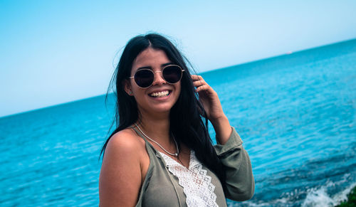 Portrait of young woman in sunglasses against sea