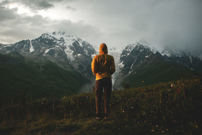 Rear view of man standing against mountain and sky