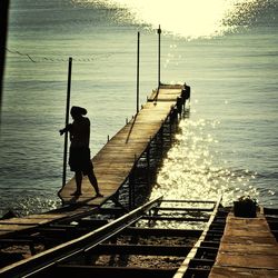 Man standing on jetty in river
