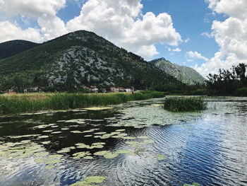 Scenic view of river by mountains against sky