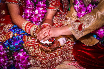 Midsection of bride and bridegroom holding hands during wedding ceremony