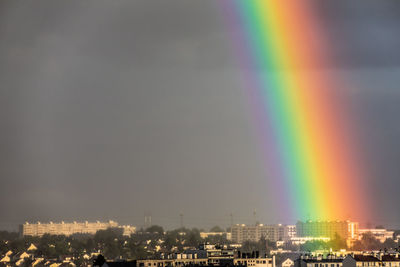 Rainbow over illuminated buildings in city against sky