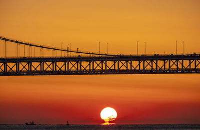 View of bridge over sea against orange sky