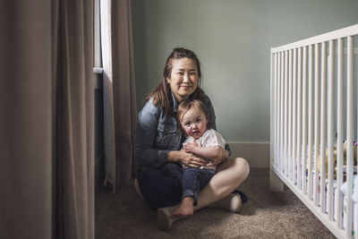 Portrait of mother hugging toddler daughter in window light