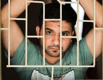 Portrait of young man standing in cage