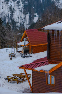 House on snow covered field by building during winter