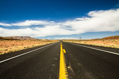 Country road on desert landscape against sky