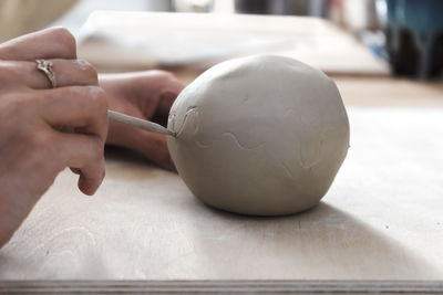 Artisan's hands with ceramic working tool or pencil sketches on ceramic.