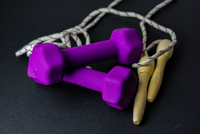 High angle view of dumbbells with jumping rope on black background