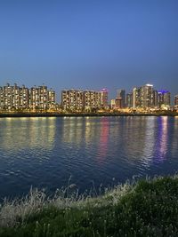 Illuminated buildings in city against clear sky