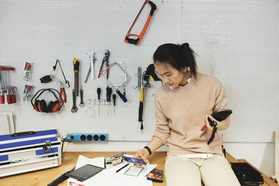 Businesswoman using smart phone while working in workshop