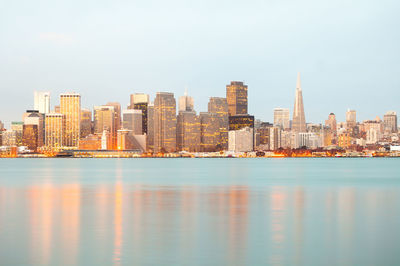 Sea by buildings against sky in city