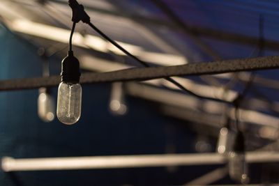 Close-up of water drop hanging from metal against sky