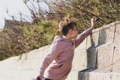 Boy reaching towards ball on plants