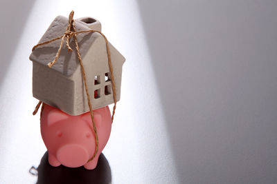 Close-up of model home tied with piggy bank on table