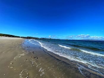 Scenic view of beach against clear blue sky