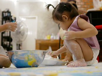 Baby preparing food while sitting on floor