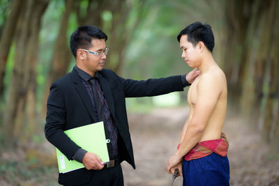 Manager discussing with shirtless worker on field