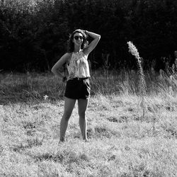 Full length portrait of young woman standing on field