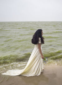 Rear view of woman at beach against clear sky