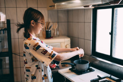 Side view of young woman holding food at home