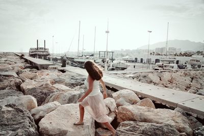 Rear view of woman on rock against sky