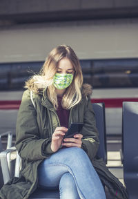 Young woman using mobile phone while sitting on seat