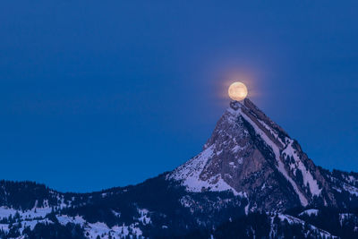 Scenic view of snowcapped mountains against clear blue sky at night