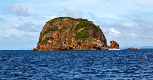 Rock formation by sea against sky