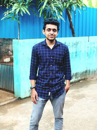 Portrait of young man standing against wall