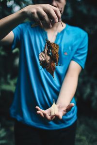 Midsection of man catching dry leaves in forest