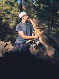 Midsection of man with dog against trees