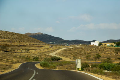 Road leading towards mountains against sky