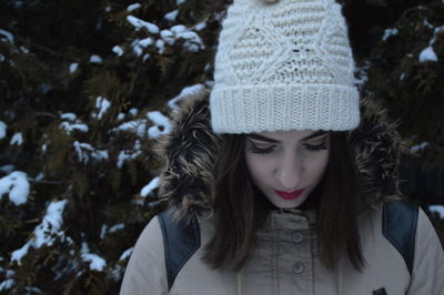 Close-up of beautiful woman wearing white knit hat against plants