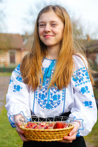 Portrait of smiling young woman standing against trees