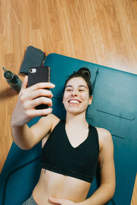 High angle view of woman doing selfie while lying on floor