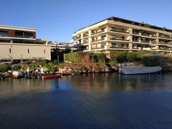 Buildings by river against clear sky