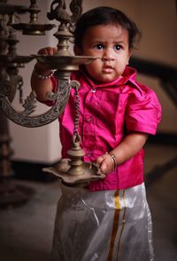 Baby girl wearing traditional clothing standing by diya