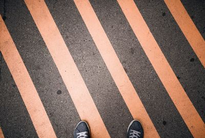 Low section of person standing on crosswalk