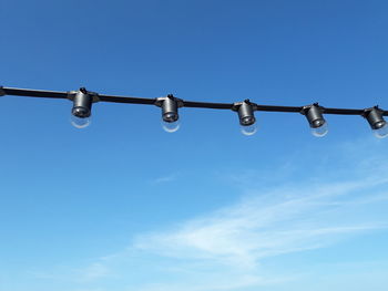 Low angle view of lighting equipment against blue sky