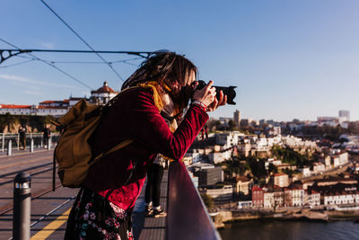 Woman in porto bridge taking pictures with camera at sunset. tourism in city europe. travel