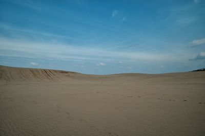 Sand dunes at beach against sky