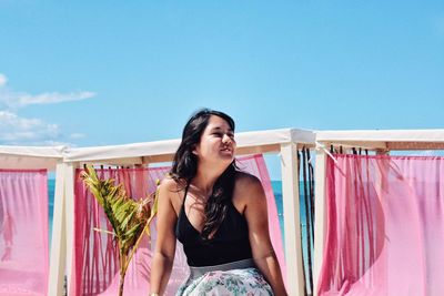 Beautiful woman sitting against blue sky