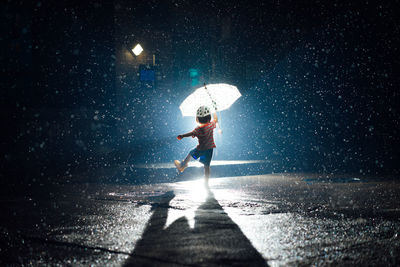 Full length of baby girl holding umbrella in rain