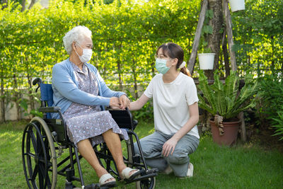 Doctor caregiver help and care asian senior woman patient sitting on wheelchair in park