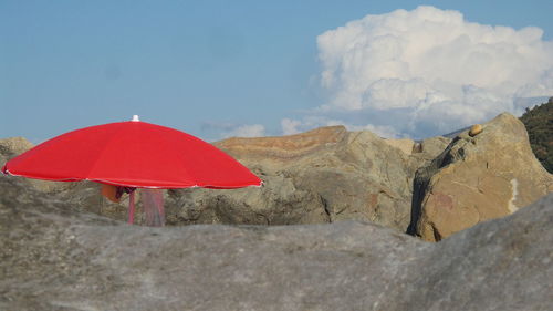 Red umbrella on mountain against sky