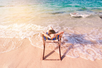 High angle view of woman sitting deck chair at beach