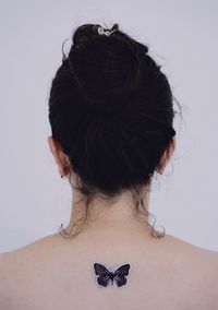 Rear view of woman with tattoo on back against white background