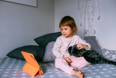 Small child watches cartoons at home on sofa on the tablet. kid use technology
