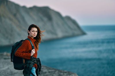 Young woman standing in sea against sky